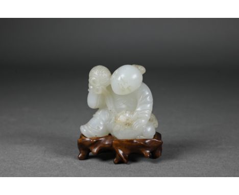 An 18th century Chinese jade carving of a boy and karashisi playing with a ribbon tied brocade ball, white stone with inclusi