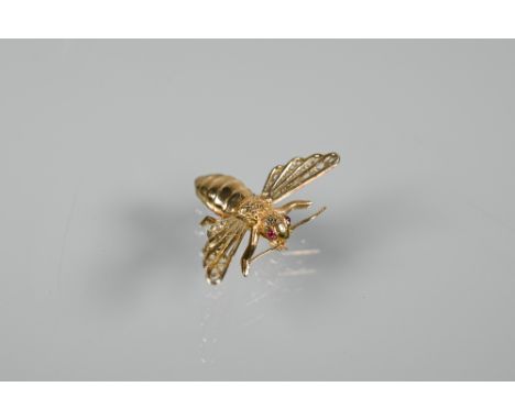 An unmarked yellow metal brooch in the form of a naturalistic flying insect with outstretched wings, cabochon ruby set eyes, 