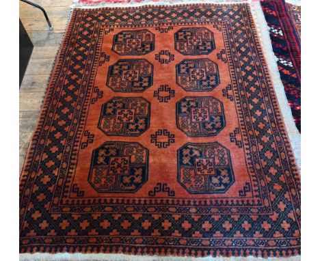 A vintage Afghan rug, the central field with two rows of large medallions on burnt orange ground, repeating geometric borders