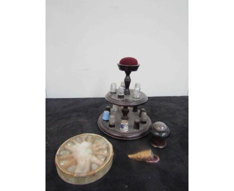 A turned wood two-tier thimble stand, two thimble cases and a collection of approximately 26 base metal, modern enamel, plast