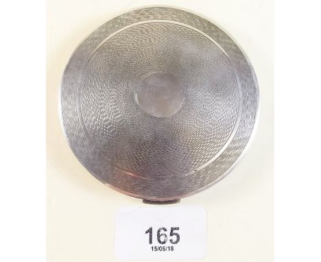 A silver compact with engine turned decoration