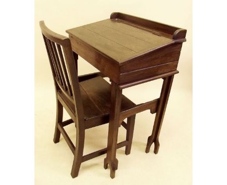 A mid 19th century dark oak school desk and slat back chair