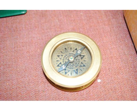 A brass compass with integral magnifying glass