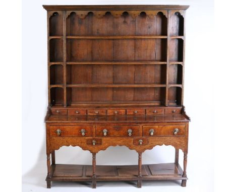 18th Century oak dresser base, the later associated rack with concave cornice above an apron and three shelves above the 18th