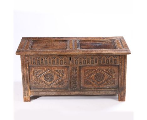 A 17th Century oak coffer, with a twin panel hinged top above a thumb craved frieze and two diamond carved panels to the fron