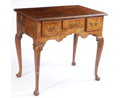 A George III fruitwood lowboy, the rectangular feather banded top with quarter panel veneers above three short drawers and ca