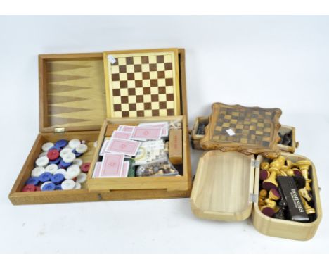 A travelling backgammon set, three chess sets and other games, the first in carved veneered case/board, 46.7cm wide, further 