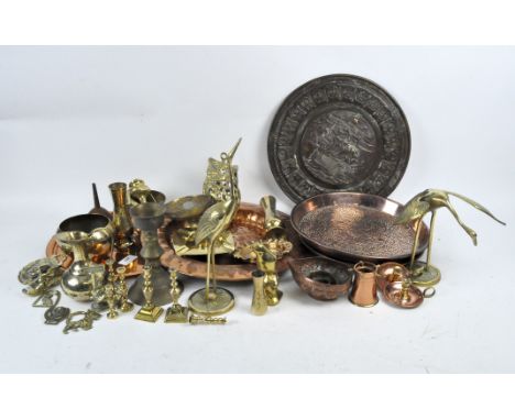 A collection of mixed brass and copper, including five chargers, horse brasses, candlestick holders, two sculptures of storks