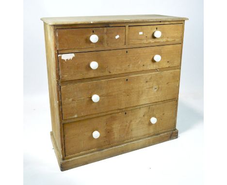 A Victorian pine chest of drawers, two short drawers above three longer ones, all with ceramic handles, raised on a plinth ba