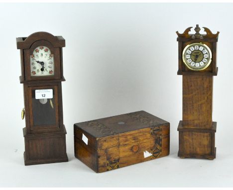 Two miniature wooden models of clocks and a hinged wooden box, one of the clocks with a battery powered movement, the other w