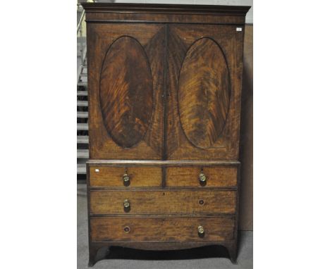 A mahogany linen press, the two doors with oval inset panels above two short and two long drawers, on bracket feet, 205cm x 1