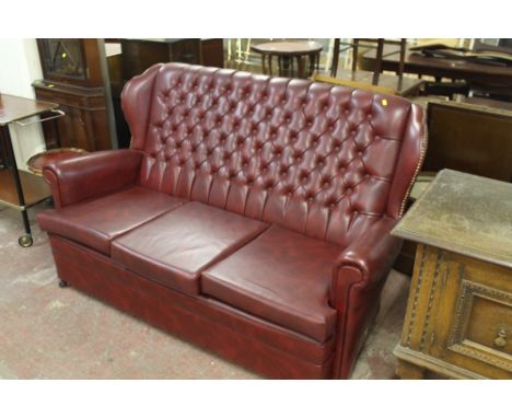 A BUTTON WINGBACK THREE SEATER SOFA IN OXBLOOD RED