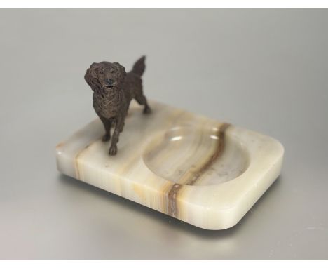 A cold-painted and patinated metal model of a standing setter, mounted on an onyx ashtray. Height overall 11cm