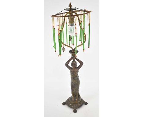 A late 19th century patinated spelter figural lamp with skeleton shade suspending several glass tassels and with numerous fur