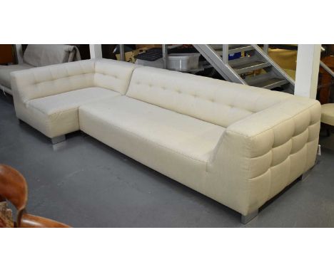 A large modern cream upholstered L-shaped corner sofa on chrome feet.