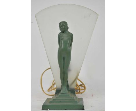 An Art Deco green patinated metal figural lamp with figure of a standing young female, a frosted fan shaped shade behind her,