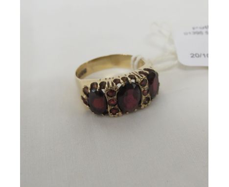 9 CARAT GOLD RING SET WITH THREE LARGE GARNETS AND FIVE SMALL GARNETS (ONE ABSENT), BRITISH HALLMARKS, MAKER'S STAMP KR, GROS