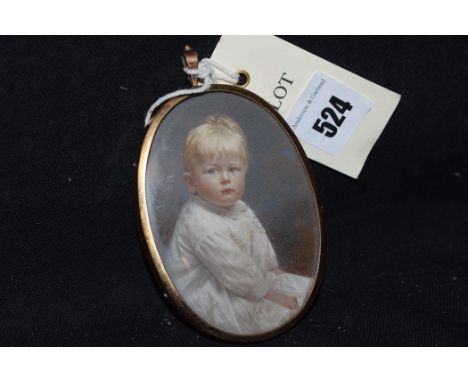 A miniature photographic portrait of a child, in gold-coloured metal pendant frame.