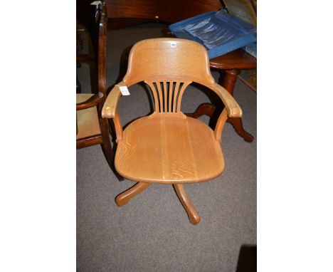An oak desk chair fitted swivel reclining mechanism, raised on castors.