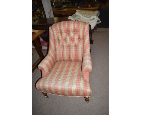 A modern easy armchair with button back, turned legs and brass castors.