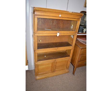 A four tier light oak Globe Wernike style stacking bookcase, triple glazed compartments and panel doors below, 56cms wide.