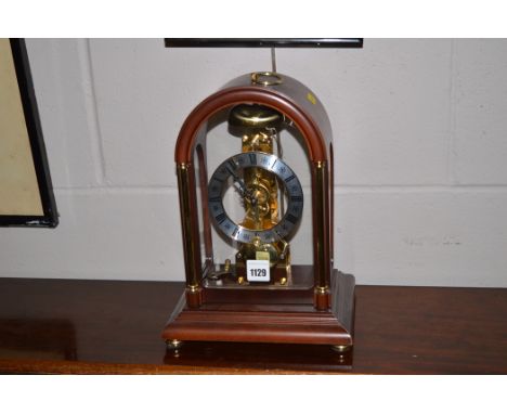 A modern mahogany and brass dome shaped glazed mantle clock with visible movement, 29cms high.