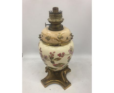 AN ANTIQUE CERAMIC AND BRASS OIL LAMP WITH FLORAL DESIGN 