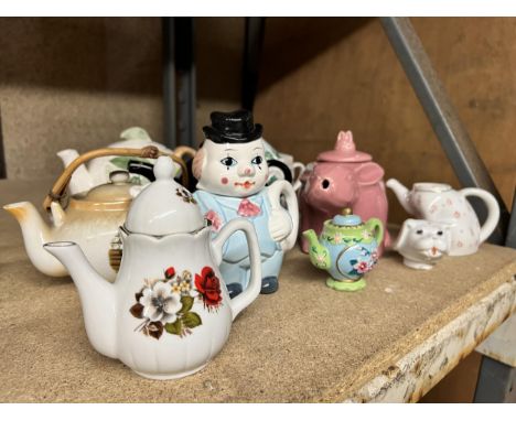 A QUANTITY OF NOVELTY TEAPOTS TO INCLUDE A RABBIT, CLOWN, FRUIT, CLOCK, ETC., 