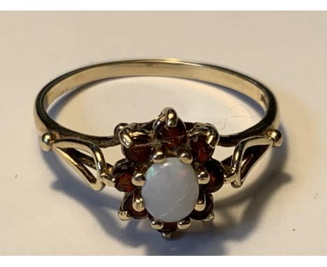 A 9 CARAT GOLD RING WITH A CENTRE OPAL SURROUNDED BY EIGHT GARNETS SIZE O GROSS WEIGHT 1.73 GRAMS 