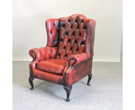 A red upholstered button back wing armchair, on cabriole legs