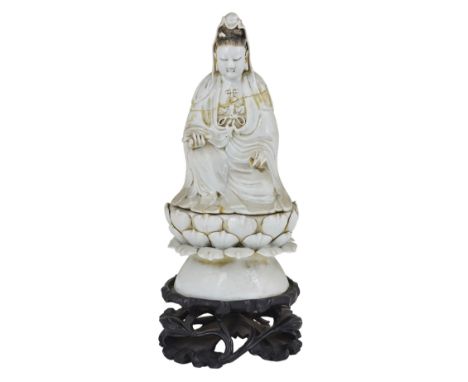 A CHINESE BLANC DE CHINE FIGURE OF GUANYIN, 19TH CENTURY seated on a loose lotus throne base, holding a scroll in her hand, t