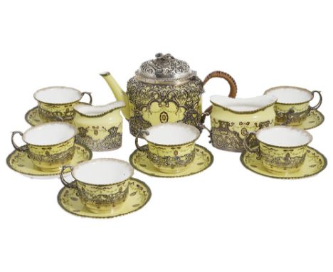 AN EDWARDIAN SILVER AND PORCELAIN THREE-PIECE TEA SET AND SIX CUPS AND SAUCERS the primrose-coloured porcelain with printed r