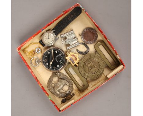 A military pocket watch with black dial, Tell manual wristwatch, collection of military badges and a belt buckle.