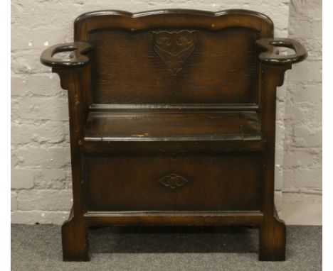 A carved oak hall seat / umbrella stick stand with under seat storage.