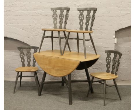 An Ercol drop leaf table, along with a set of four matching chairs with grey painted legs.