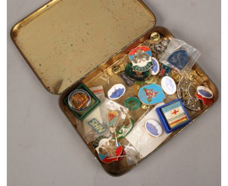An advertising tin and contents of mostly enamel pin badges.