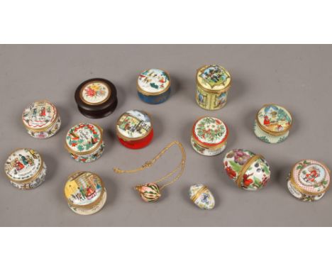 A collection of mainly Christmas themed enamel pill boxes, along with enamel watch pendant.