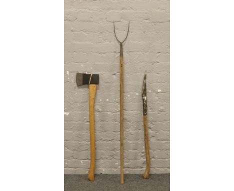 Three agricultural tools; woodman's axe, hedging bill and a pitch fork.