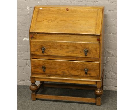 A carved light oak bureau over two drawer base raised on bulbous legs.