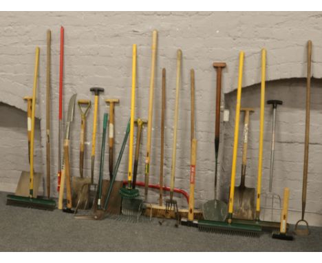 A large collection of garden hand tools; shovels, spades, brushes and saws.