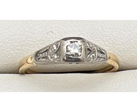 An Art Deco 18ct gold and platinum 0.05ct diamond solitaire ring with leaf pattern to shoulders. Gold marks to inside of band