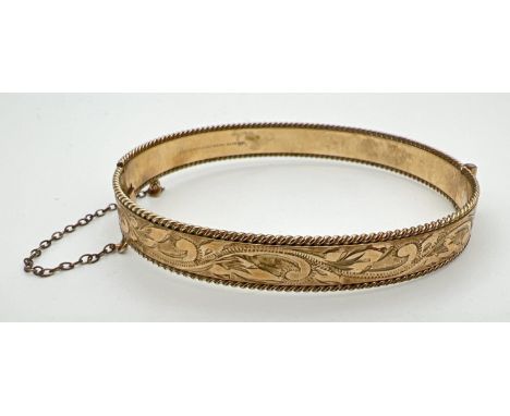 A vintage 9ct rolled gold bangle with floral engraving, push clasp and safety chain. Marks to inside of bangle. Approx. 6cm d