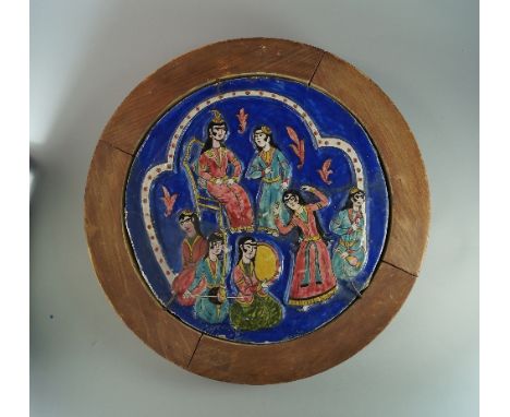 A Persian pottery circular tile, 19th century, moulded and painted with a nobleman and his retinue, in a wooden frame, the ti