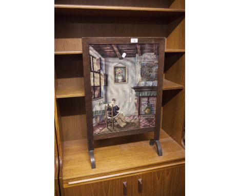 A VICTORIAN FIRE SCREEN, OAK FRAME WITH NEEDLEWORK SCENE OF A SEATED WOMAN READING 