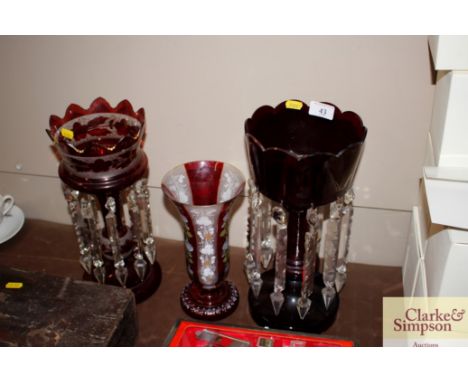 Two Victorian ruby glass lustre vases and a similar decorated vase