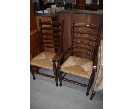 A pair of tradtional oak ladder back carver chairs having rush seats