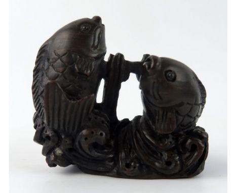 A Japanese carved and stained hardwood netsuke in the form of two leaping carp, unsigned, 5cm wide. 