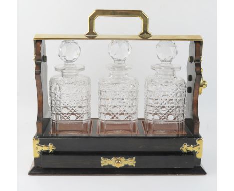 A Betjemann's patent rosewood and brass bound tantalus, of rectangular outline containing three clear glass decanters and sto