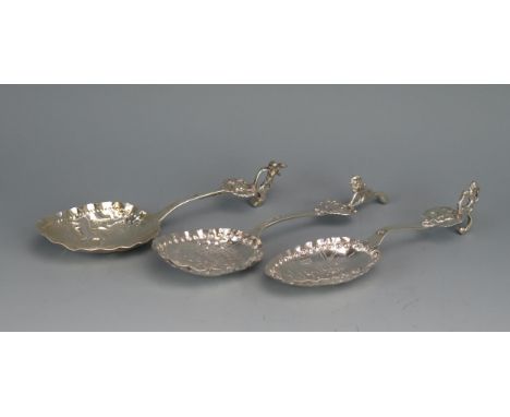 Three Dutch silver spoons, stamped marks, the bowls decorated with figures in village scenes, having lion terminals, each 14.