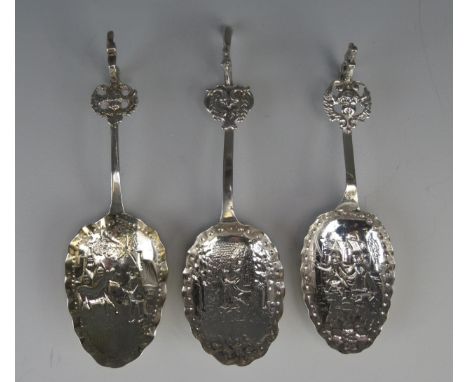 Three Dutch silver spoons, stamped marks, the bowls decorated with figures in village scenes, having lion terminals, each 14.